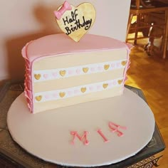 a pink and white birthday cake with hearts on top