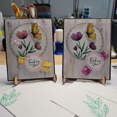 two cards with flowers on them sitting on a table