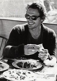 a black and white photo of a man sitting at a table with food in front of him