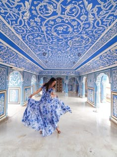 a woman in a blue and white dress is walking through an ornately painted room