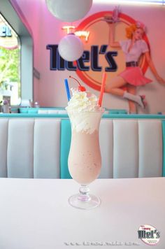 a tall glass filled with ice cream and whip cream on top of a white table