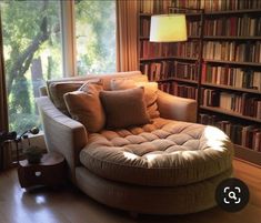 a living room filled with furniture and bookshelves next to a window covered in lots of books