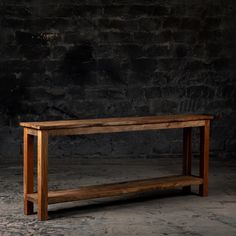 a wooden bench sitting on top of a stone floor next to a black brick wall