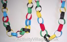 two necklaces made out of colored paper on a white surface with one chain attached to the other