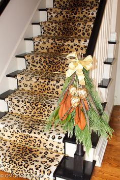 a decorated christmas tree sitting on top of a banister next to a leopard print stair case