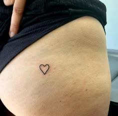 a woman with a small heart tattoo on her thigh