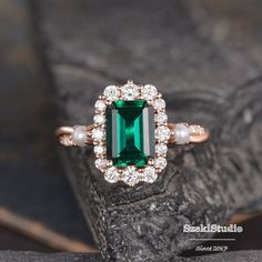 an emerald and pearl ring sitting on top of a rock