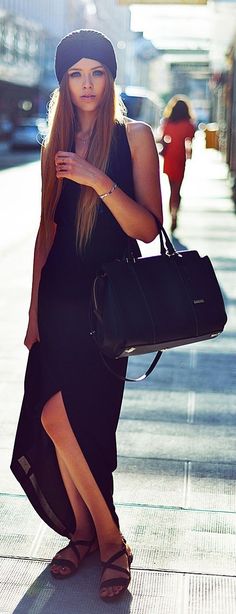 a woman is walking down the street with a handbag on her shoulder and wearing a hat