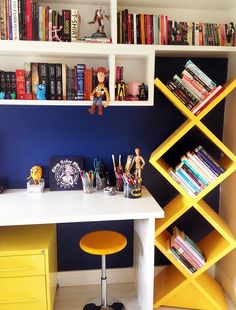 a white desk topped with yellow books next to a shelf filled with lots of books