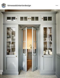 an open door leading into a kitchen with white cabinets and glass doors on both sides