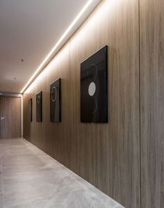 an empty hallway with wooden walls and artwork on the wall, along with marble flooring