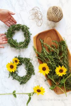 two hands are holding wreaths with sunflowers on the table next to them