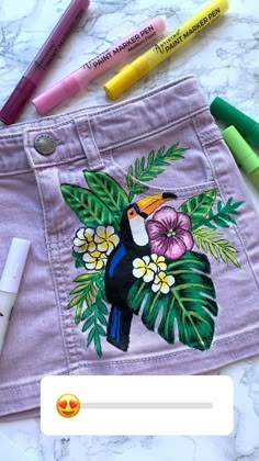 some crayons are laying next to a pair of pink shorts with a bird on it