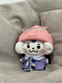 a small stuffed animal wearing a pink hat and glasses on top of a gray couch