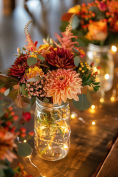 flowers are in mason jars with fairy lights on the table next to eachother