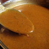 a spoon full of brown liquid sitting on top of a pan