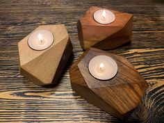 three small wooden candles are sitting on a wood table with one candle in the middle