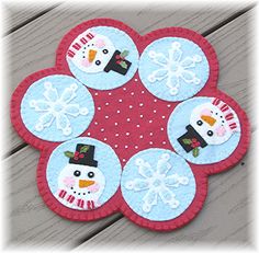 four snowman coasters sitting on top of a wooden table