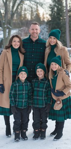 a man and two women standing next to a little boy in the snow wearing matching outfits