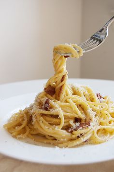 a fork full of spaghetti with bacon and parmesan cheese