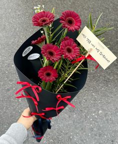 a person holding a bouquet of flowers with a sign attached to the end of it