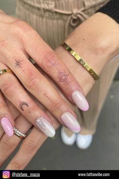 two hands with different designs on them holding each other's fingers and their rings