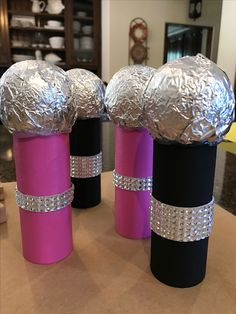 three rolls of tin foil wrapped in black, pink and silver are sitting on a table