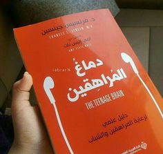 a person holding up a red book in their hand with arabic writing on the cover