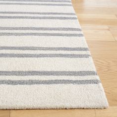 a white and gray striped rug on the floor with wood floors in the background,