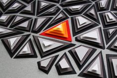 an abstract piece of art made out of black and white paper with red triangle in the middle