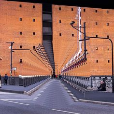 an unusual staircase made out of steps in front of a brick building with people walking on the sidewalk