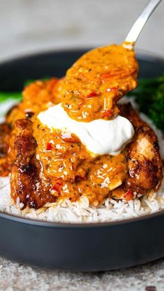 a bowl filled with rice and meat covered in sauce on top of broccoli