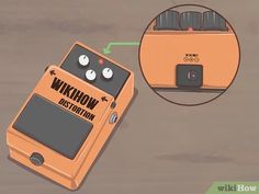 an orange electric guitar pedal sitting on top of a wooden floor next to a black and white button