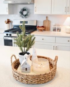 a small christmas tree in a wicker basket on a kitchen counter with white cabinets