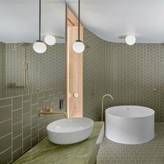 a bathroom with green tiles and a white bowl sink in the middle of the room