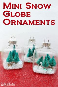 three glass ornaments with trees in them on a red tableclothed surface and the words globe ornaments written below