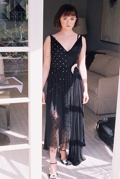 a woman in a black dress standing on a porch