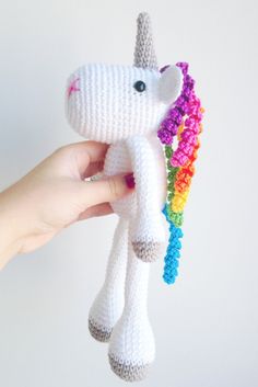 a crocheted unicorn toy being held by someone's hand