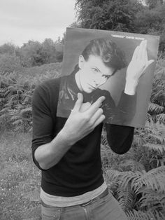 a young man holding up a photo in front of his face