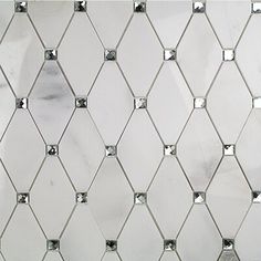 a white tiled wall with diamond shaped tiles on it's sides and silver rivets around the edges