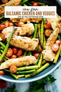 chicken and veggies in a pan with tomatoes, asparagus and parsley