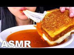 a woman eating a grilled cheese sandwich with tomato soup