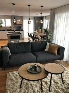 a living room filled with furniture next to a kitchen and dining room table in front of a window