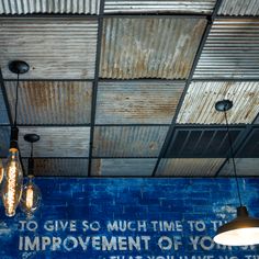 some lights hanging from the ceiling in front of a blue wall with words on it