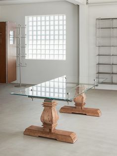 two glass tables with wooden bases in an empty room