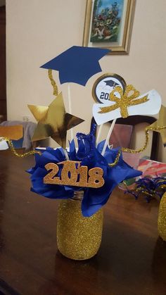 two vases filled with gold and blue decorations on top of a wooden table next to a clock