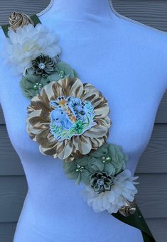 a white mannequin torso with flowers and an elephant brooch on it's back