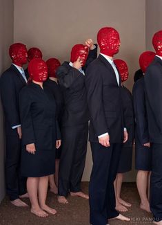 a group of people with red masks on their heads standing in front of each other