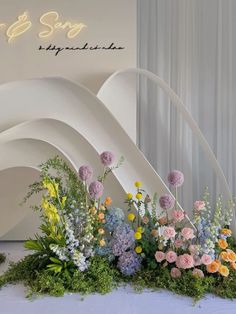 an arrangement of flowers on display in front of a white wall