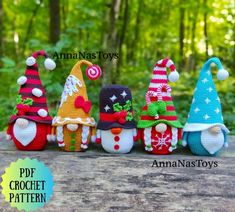 crochet christmas gnomes are lined up on a wooden table in the woods